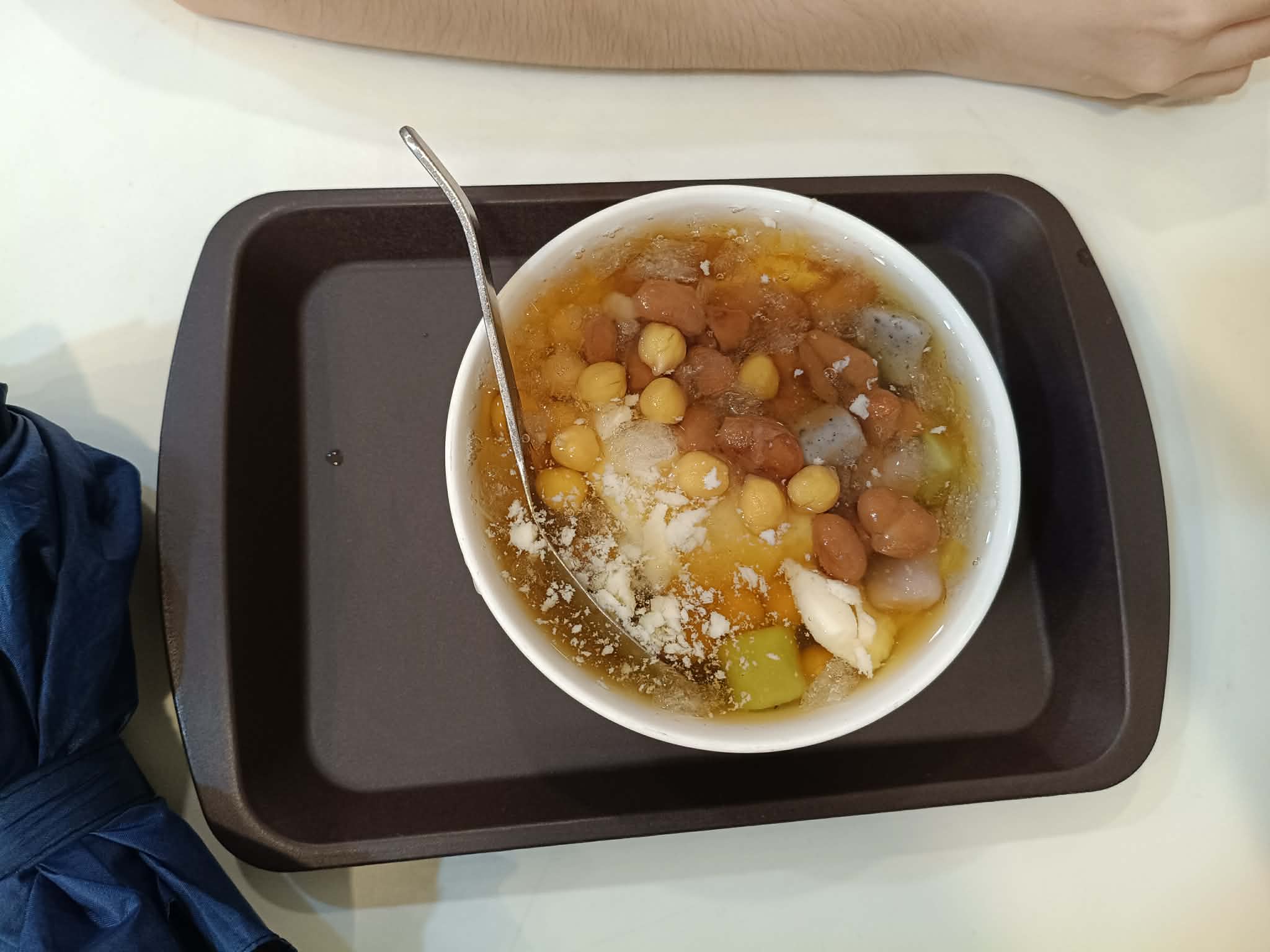 A bowl of warm douhua dessert soup with peanuts and taro and sweet potato balls
